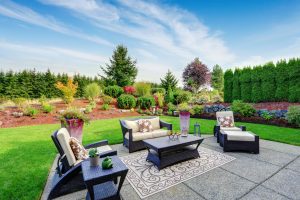 Impressive backyard landscape design. Cozy patio area with settees and table