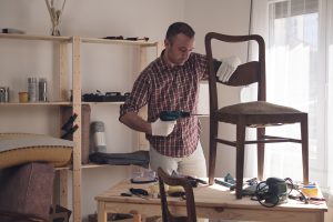 Man working in a small home workshop for furniture repairing and restoration.