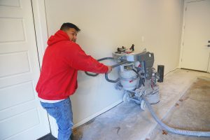 man in red sweatshirt working on basement flooring